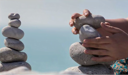 person stacking rocks at the seaside